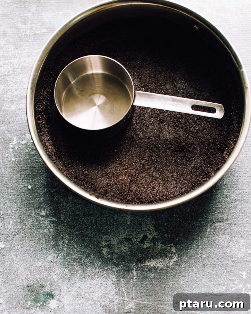 Effortless Chocolate Silk Tart 4 Hands pressing chocolate cookie crumbs into a tart pan for the crust.