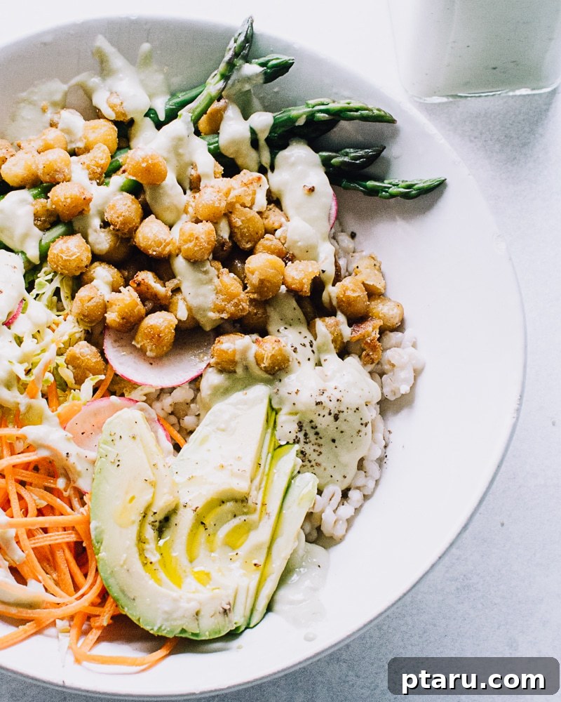 Tangy Lemon Yogurt Sauce 4 A vibrant nourish bowl generously topped with creamy lemon yogurt sauce, featuring various colorful vegetables and grains.