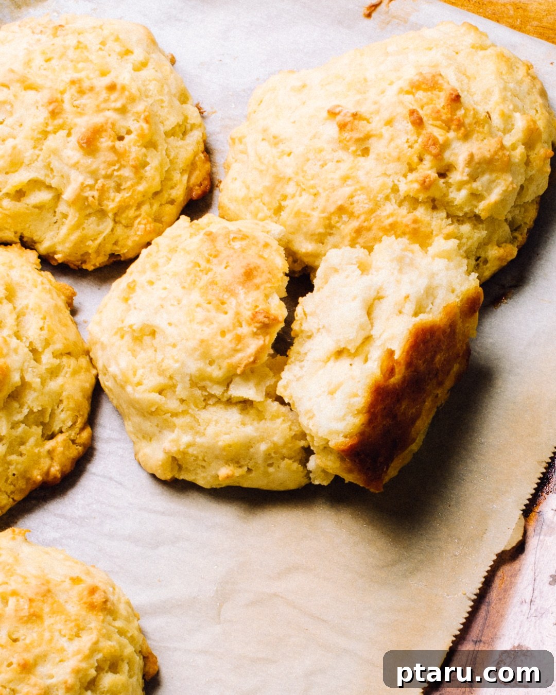 Cloud-Like Buttermilk Drop Biscuits 6 Five beautifully golden and risen buttermilk drop biscuits displayed prominently on a baking sheet.