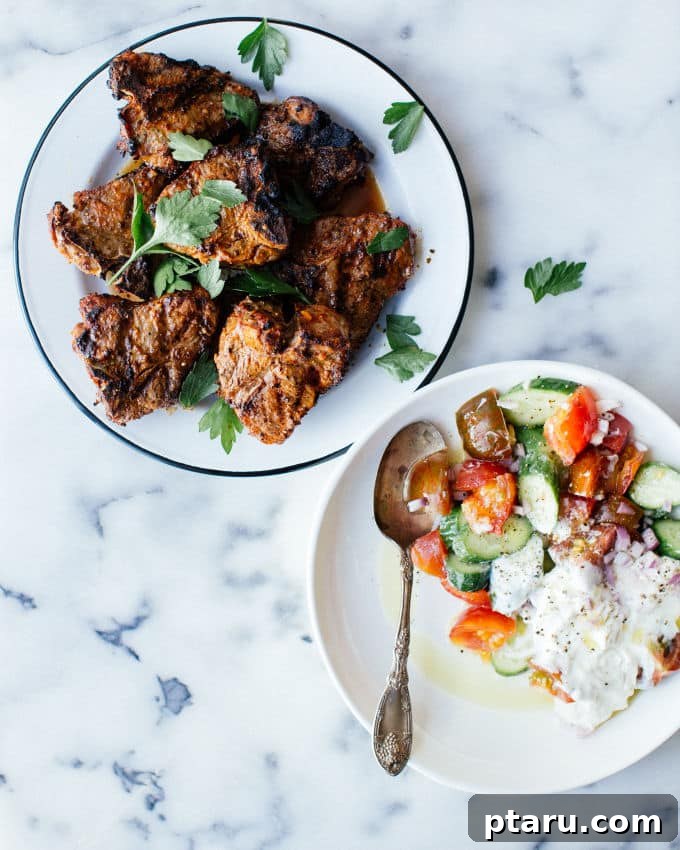 Harissa-Kissed Lamb Chops with a Zesty Cucumber-Yogurt Salad 2 Juicy grilled harissa lamb chops resting on a cutting board, garnished with fresh herbs.
