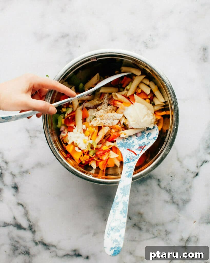 Mediterranean Pasta Salad with Whipped Feta 4 Step-by-step image showing cooked pasta and vegetables being tossed for healthy pasta salad