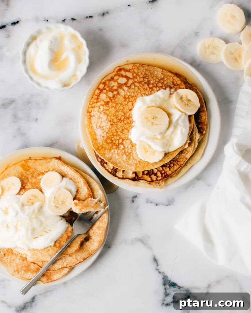 Three Ingredient Banana Pancake Delight 2 Finished 3-Ingredient Banana Pancakes on plates with yogurt and bananas.
