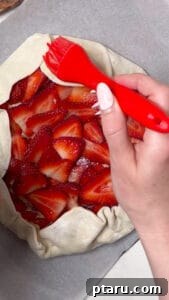 Apply egg wash and sugar to strawberry tart crust.