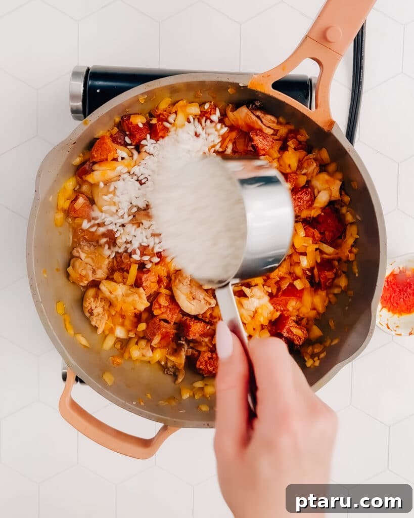Spanish Surf and Turf Paella 4 Adding Arborio rice to the pan with sautéed chicken, chorizo, and aromatics, ready to absorb the rich broth.