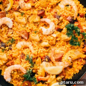 Spanish Surf and Turf Paella 6 A top-down view of the finished Chorizo Paella with shrimp and chicken, garnished with fresh herbs.