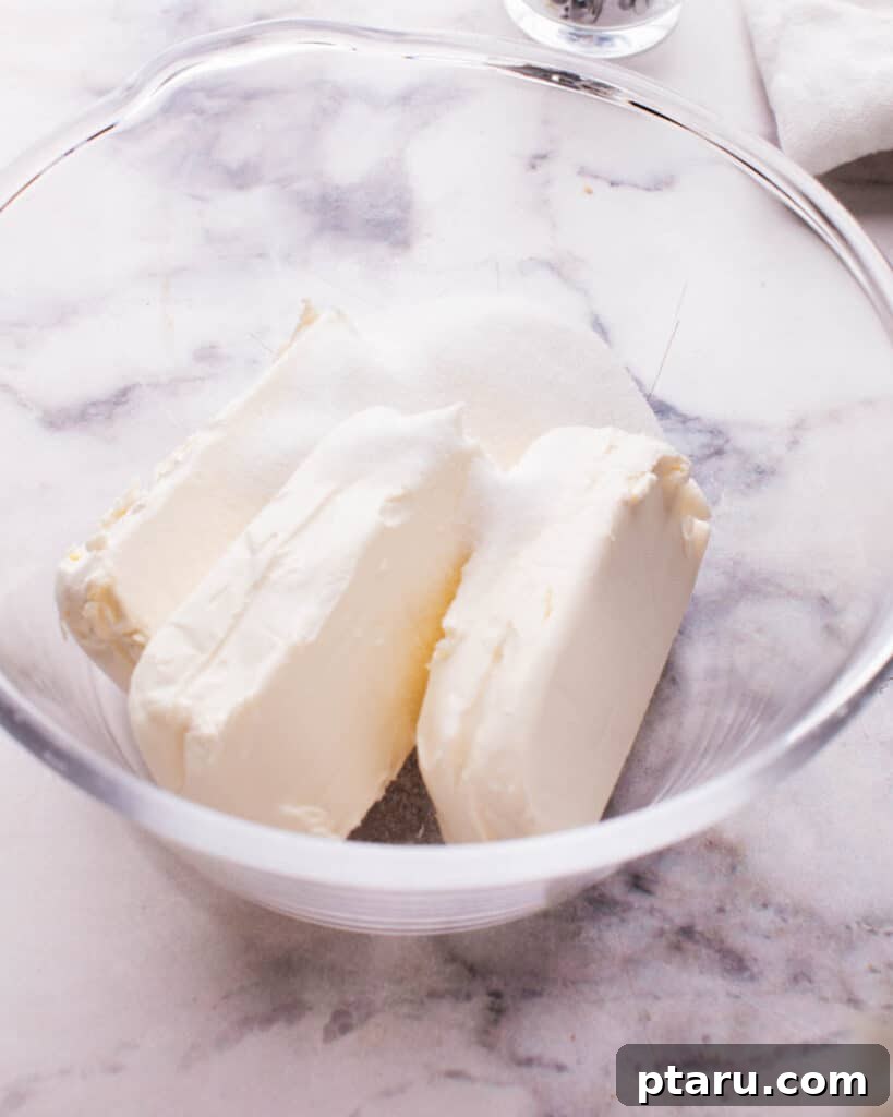 Effortless Cloud Cheesecake 4 Softened cream cheese in a mixing bowl, ready to be whipped into a smooth cheesecake filling.