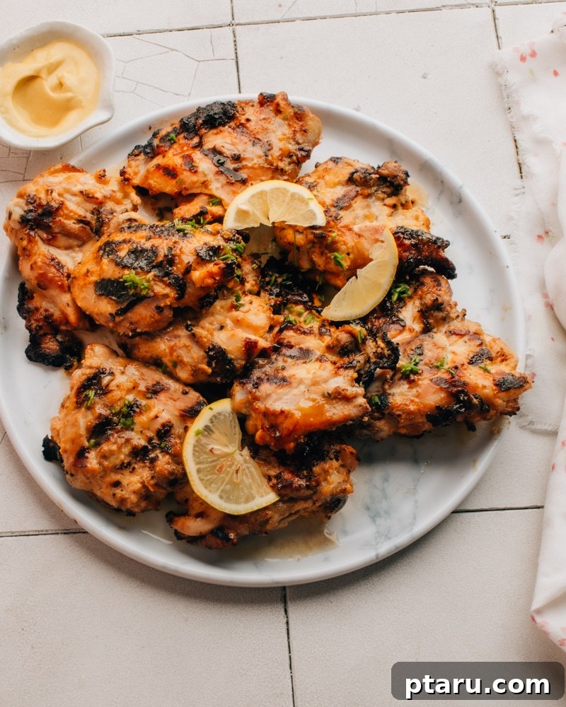 Golden Glazed Honey Mustard Chicken Thighs 2 Grilled Honey Mustard Chicken on a plate, garnished with fresh herbs.