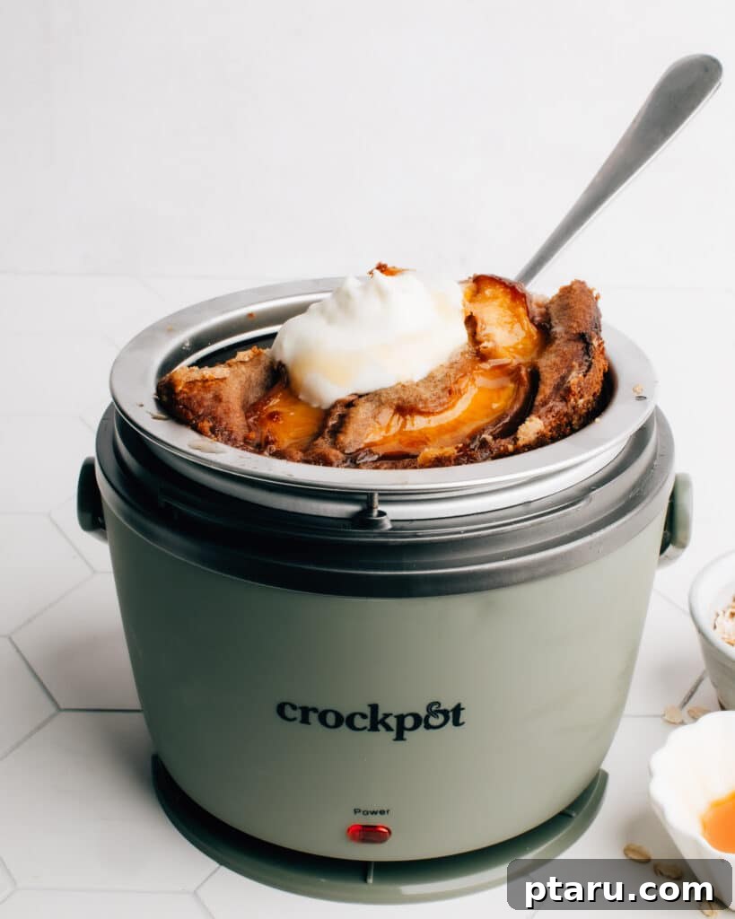 Cozy Morning Crockpot Oatmeal 2 A delectable serving of overnight Crockpot Slow Cooker Baked Oats, topped with juicy peach slices, ready to be enjoyed as a wholesome breakfast.