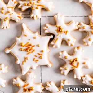 Snowflake cookies with royal icing and sprinkles on a table.