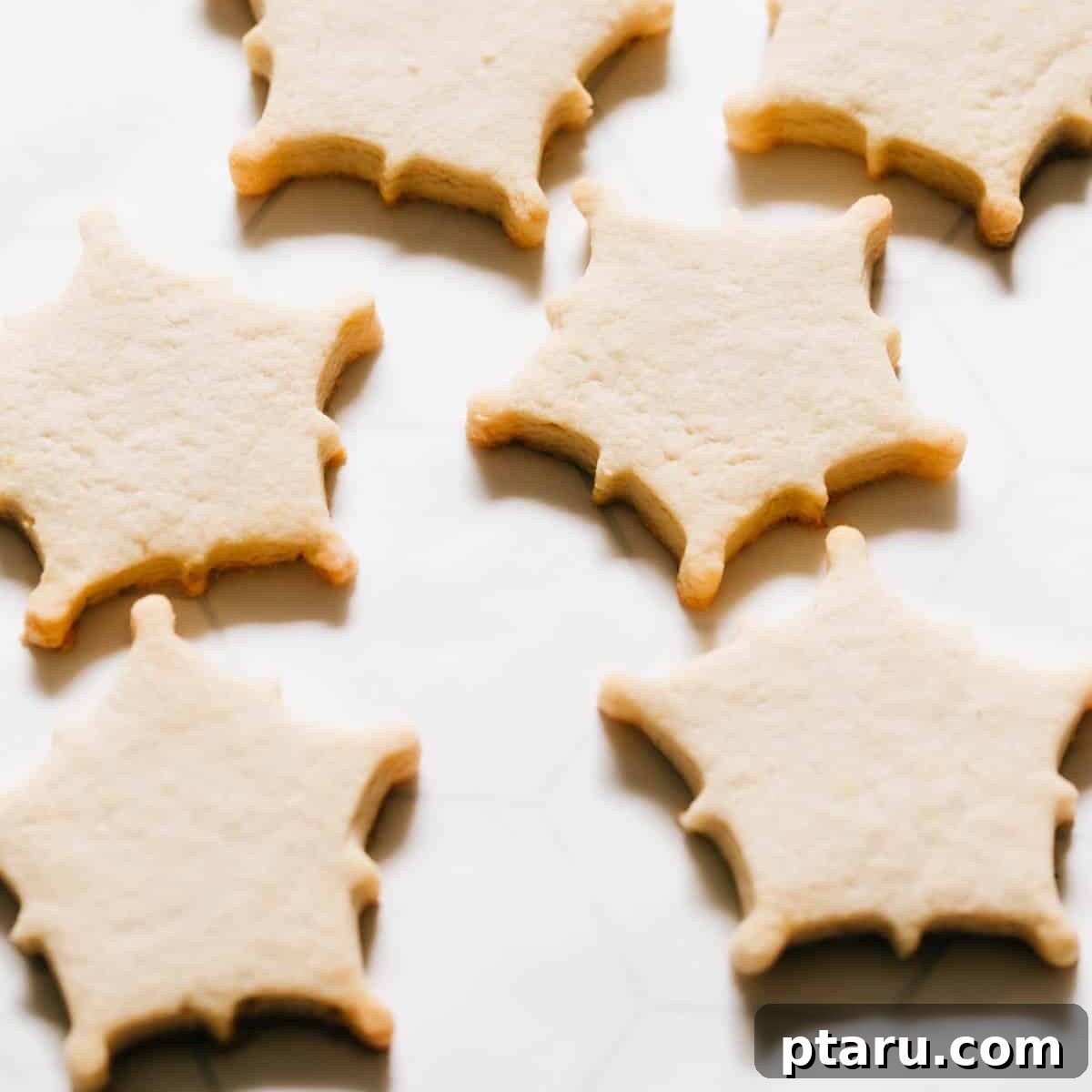 Glistening Snowflakes 3 Baked, undecorated snowflake cookies neatly arranged on parchment paper, awaiting their royal icing.