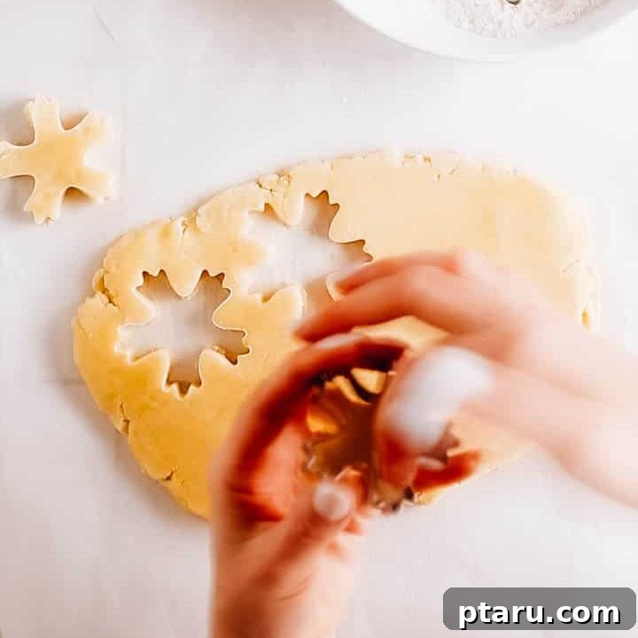 Glistening Snowflakes 7 Cutting out snowflake shapes from rolled-out cookie dough using a cookie cutter.