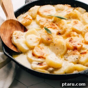 Gluten-free potatoes au gratin in a cast iron pan with serving spoon.