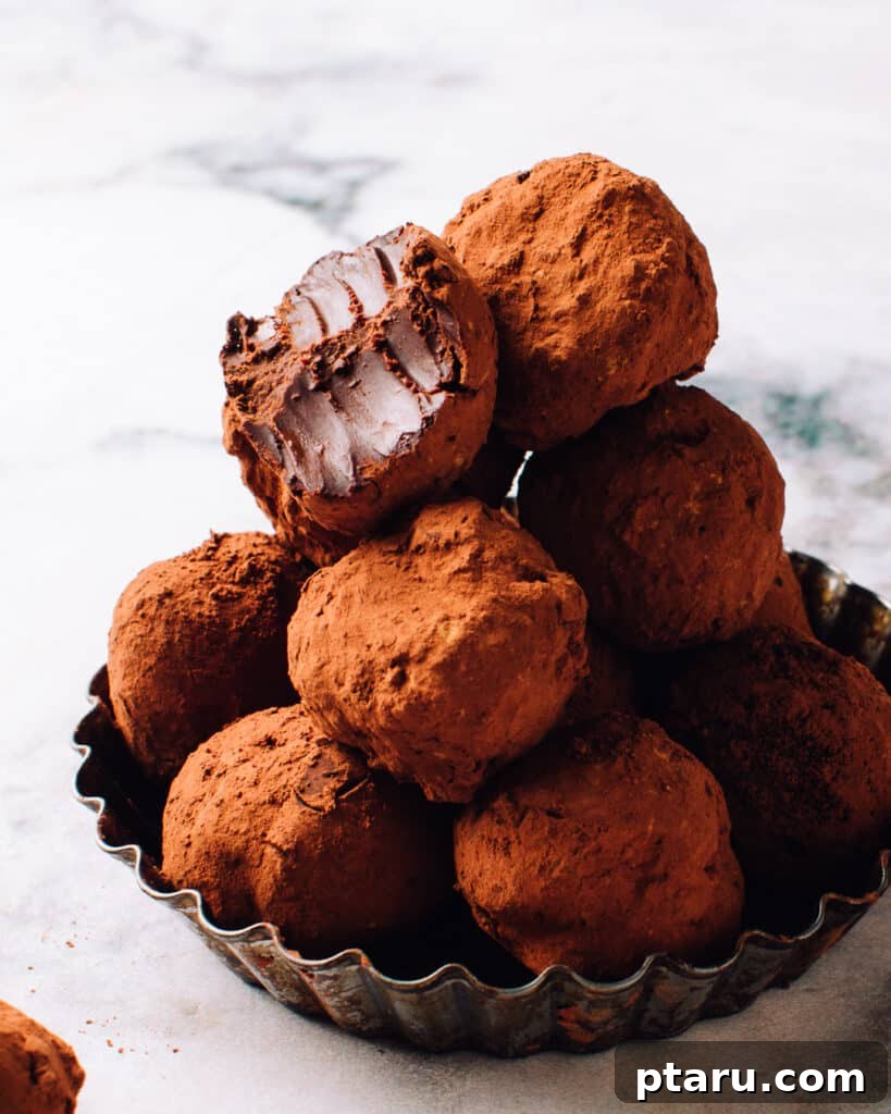 Effortless Festive Bites: 15+ No-Bake Christmas Sweets 2 3 ingredient easy Chocolate truffles on a serving plate, one with a bite out.