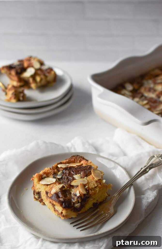 15 Irresistible Italian Desserts to Sweeten Your Christmas 11 A portion of rich Panettone bread pudding, beautifully served on a plate with a fork, showcasing its warm, custardy texture and fruit-studded charm, a perfect holiday comfort dessert.