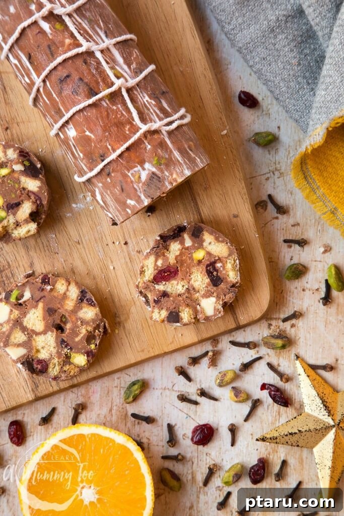 15 Irresistible Italian Desserts to Sweeten Your Christmas 12 Slices of festive Christmas Spiced Chocolate Salami, revealing a beautiful mosaic of cranberries, pistachios, and chocolate, artfully arranged on a wooden board.