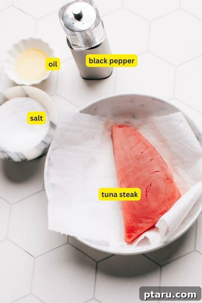 Effortless Air Fryer Tuna Steaks 3 Ingredients for Air Fryer Tuna Steak arranged on a kitchen countertop, including tuna steak, salt, black pepper, and oil.