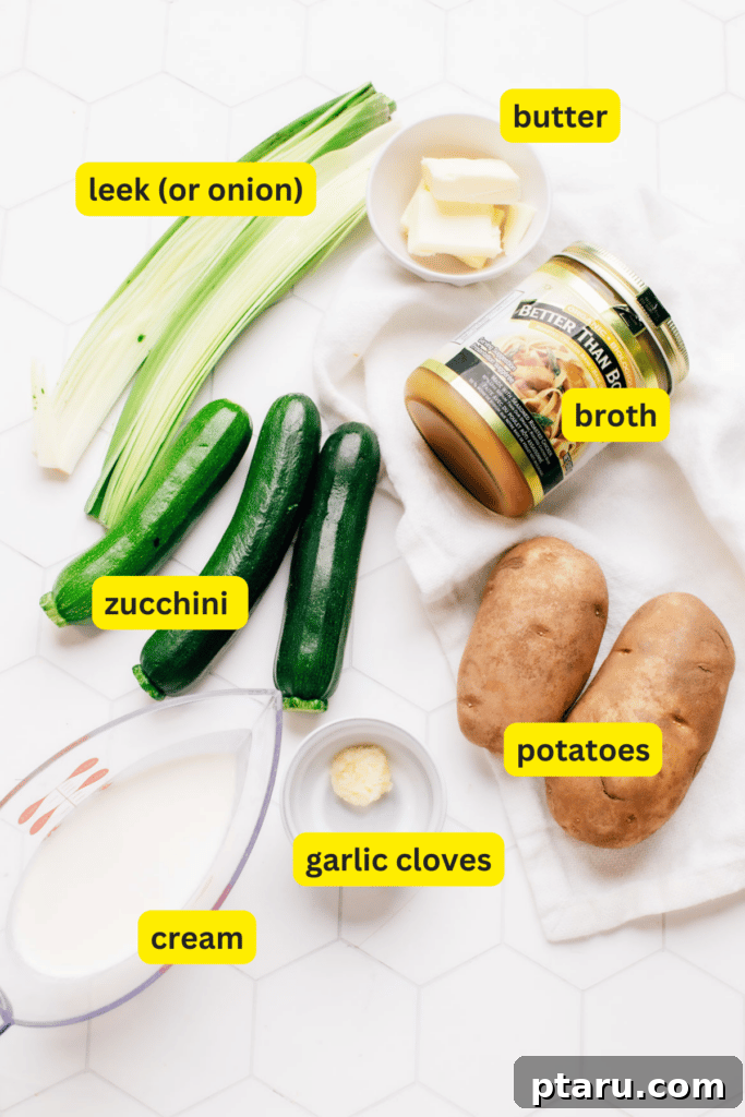Silky Zucchini Potato Velouté 3 A collection of fresh, simple ingredients for potato zucchini soup neatly arranged on a kitchen countertop, including russet potatoes, green zucchini, a leek, garlic cloves, a stick of butter, and a carton of broth.