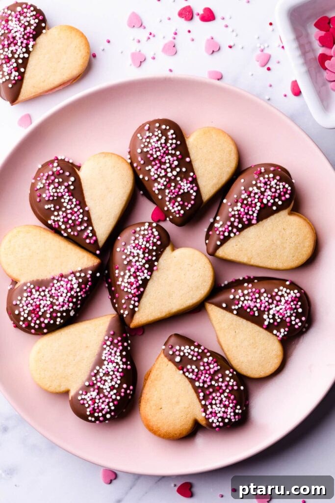 Love at First Bite: Simple Valentine's Sugar Cookies 6 Delightful sandwiched sugar cookies, adorned with festive sprinkles and a creamy filling, arranged on a charming pink plate.