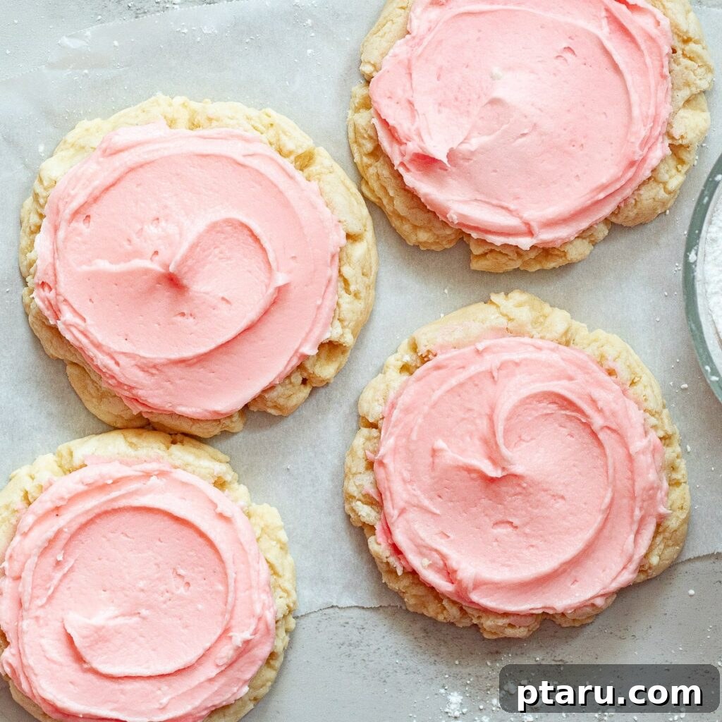 Love at First Bite: Simple Valentine's Sugar Cookies 7 Soft and delicious copycat Crumbl sugar cookies with almond frosting, neatly arranged on parchment paper.