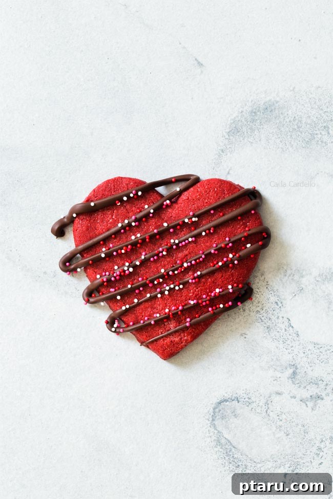 Love at First Bite: Simple Valentine's Sugar Cookies 8 Beautiful heart-shaped red velvet sugar cookies, elegantly drizzled with melted chocolate, set against a festive backdrop.