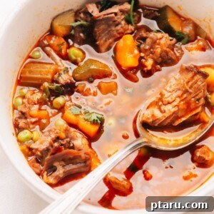Close up photo of a spoonful of beef vegetable soup, showcasing the tender beef and vibrant vegetables.