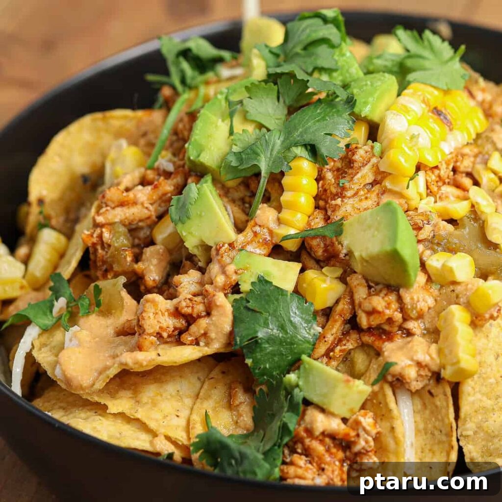 Epic Game Day Nachos: 15 Simple Recipes for Your Crowd 16 Loaded Chicken Enchilada Nachos served in an elegant black bowl, showcasing the rich sauce and abundant toppings.