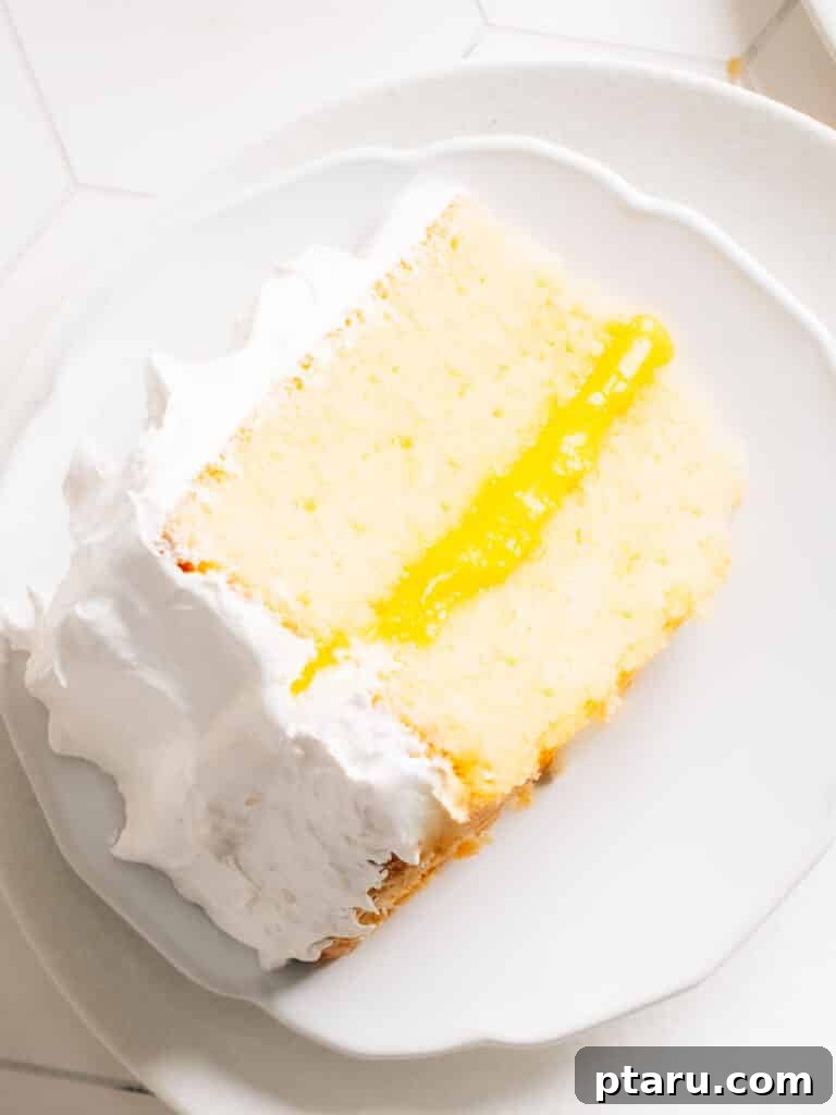 Zesty Lemon Dream Cake 2 A beautiful slice of Lemon Curd Cake showing soft lemon cake layers, a vibrant lemon curd filling, and fluffy white frosting.