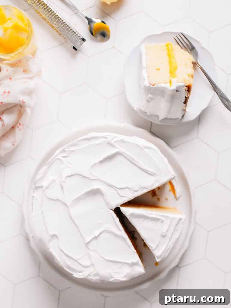Zesty Lemon Dream Cake 3 A scrumptious Lemon Curd Cake has been expertly sliced and plated on a pristine white dish, accompanied by a fork, ready to be enjoyed.