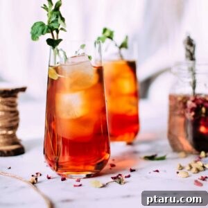 Rose and Cardamom Cocktail with a dark background, garnished with fresh rose petals.