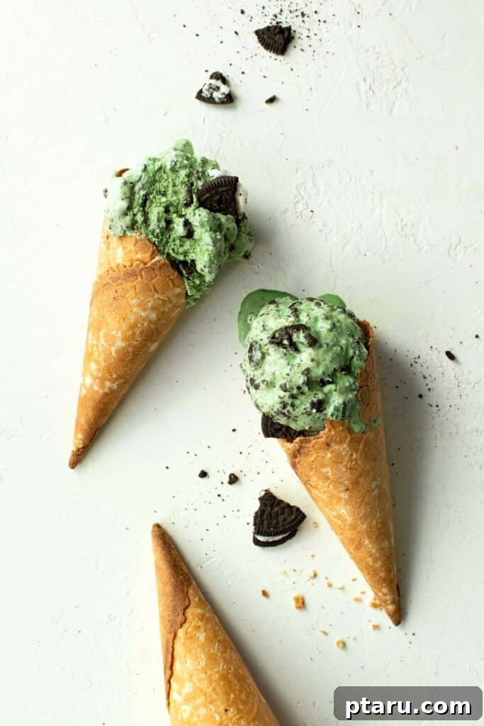 Get Lucky with These Green St. Patrick's Day Desserts 13 Two golden-brown waffle cones, each generously overflowing with scoops of creamy, vibrant green fresh mint Oreo ice cream, dotted with dark cookie pieces, presented enticingly for a refreshing treat.