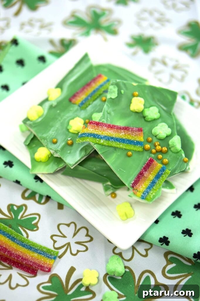 Get Lucky with These Green St. Patrick's Day Desserts 14 A stack of colorful St. Patrick's Day Leprechaun Bark pieces, featuring vibrant green chocolate, shamrock marshmallows, and various festive sprinkles, neatly arranged on a white plate, ready for a joyful celebration.