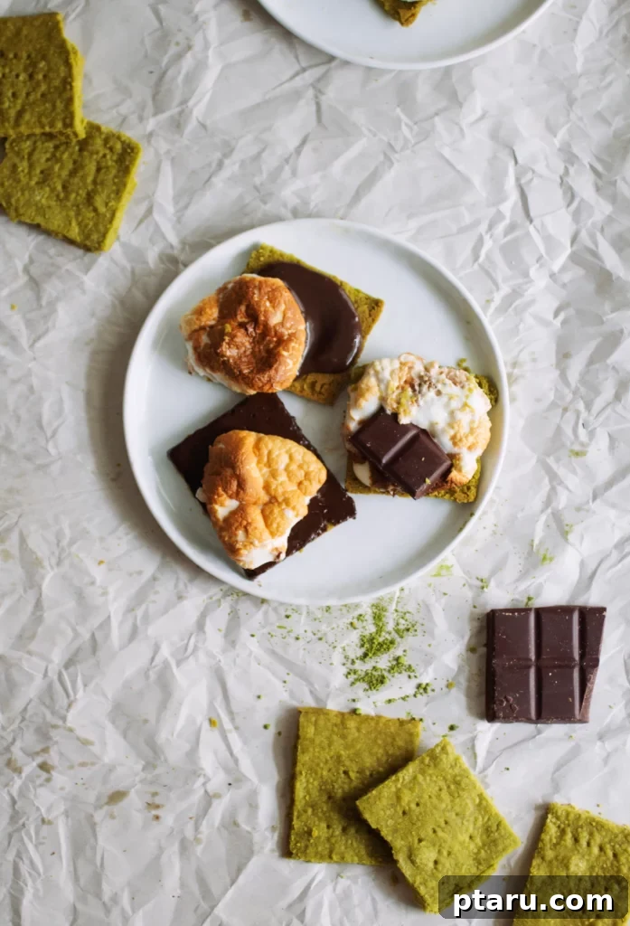 Get Lucky with These Green St. Patrick's Day Desserts 9 A white plate holds several irresistible Matcha Shortbread S'mores, with the green shortbread cookies peeking out from under perfectly toasted marshmallows and melted chocolate, creating a visually appealing and delicious dessert.
