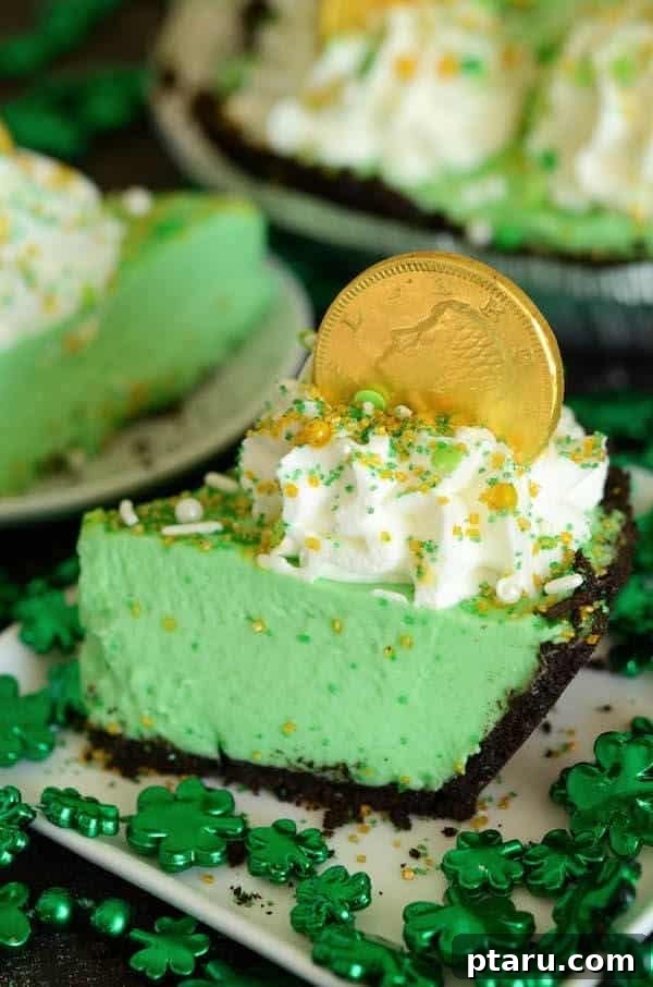 Get Lucky with These Green St. Patrick's Day Desserts 10 A pristine slice of No-Bake Shamrock Freezer Pie is presented on a white plate, showcasing its creamy green filling, a crisp crust, and a crowning swirl of whipped cream adorned with a festive chocolate gold coin.