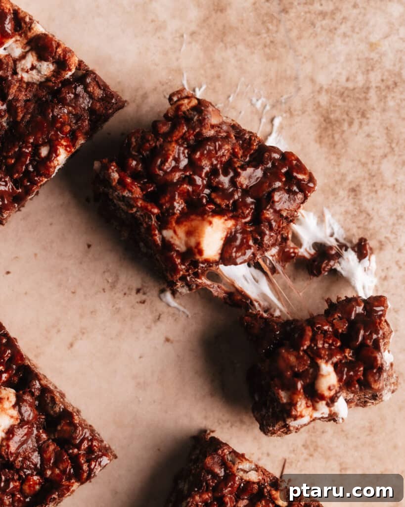 Decadent Chocolate Crunch Bars 10 Chocolate rice krispie treat cut into 2 pieces, revealing the gooey melted marshmallows and chocolate chips in its texture.