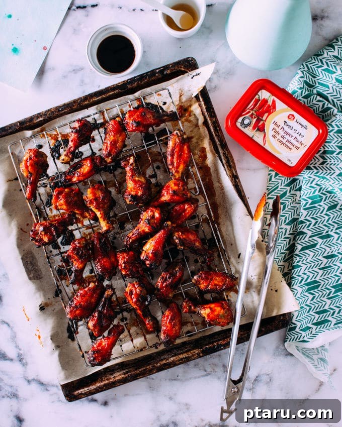 Gochujang Glazed Chicken Wings 4 Crispy oven-baked chicken wings arranged on a wire rack over a baking sheet, ready for glazing.
