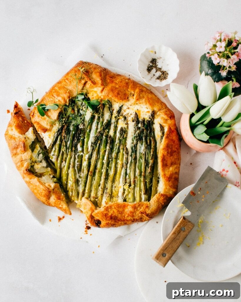 Golden Asparagus Puff Pastry Tart 2 A golden brown Asparagus Puff Pastry Tart with creamy ricotta and lemon, with one slice removed revealing the flaky layers.