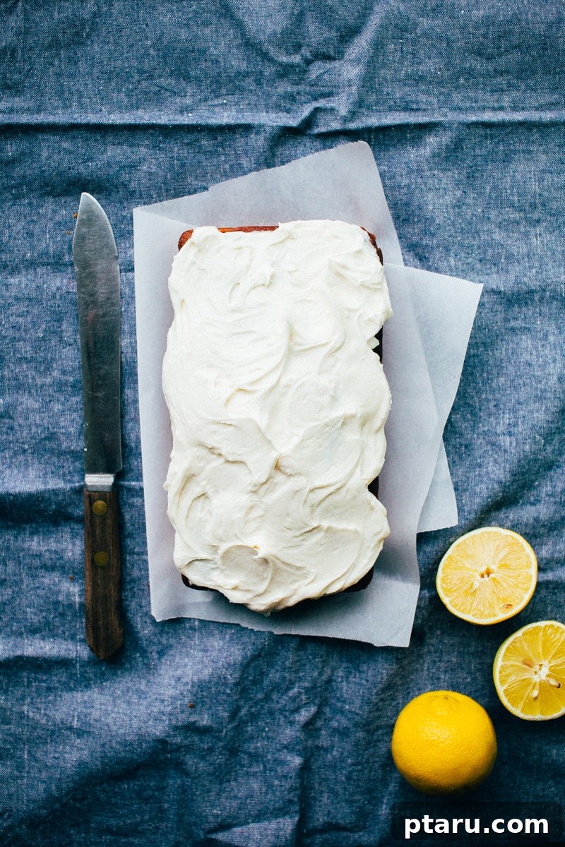 Sunshine Lemon Pound Cake 4 A slice of lemon pound cake with visible layers of cake, glaze, and frosting, ready to be enjoyed.