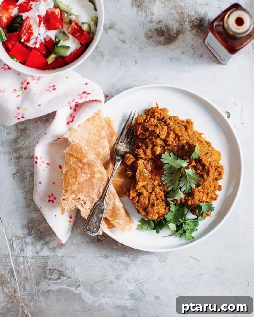 Hearty Black Chickpea Curry 2 A vibrant bowl of Kala Chana (Black Chickpea Curry) garnished with fresh cilantro, served alongside fluffy basmati rice and warm naan bread.