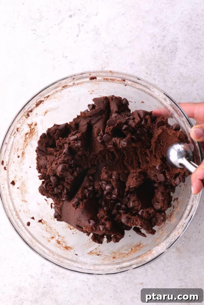 Decadent Mint Chocolate Fudge Cookies 6 Scooping balls of rich mint chocolate chip cookie dough onto a baking sheet, ready for freezing or baking.