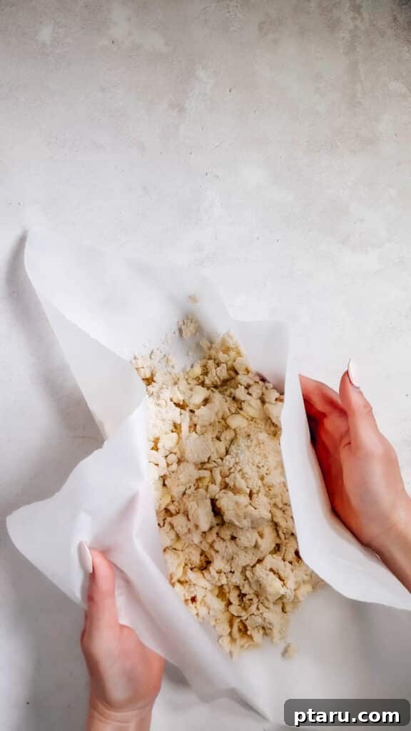 Simple Hand-Mixed Pie Crust 12 Using parchment paper to gently press and fold the dough mixture into a cohesive disc.