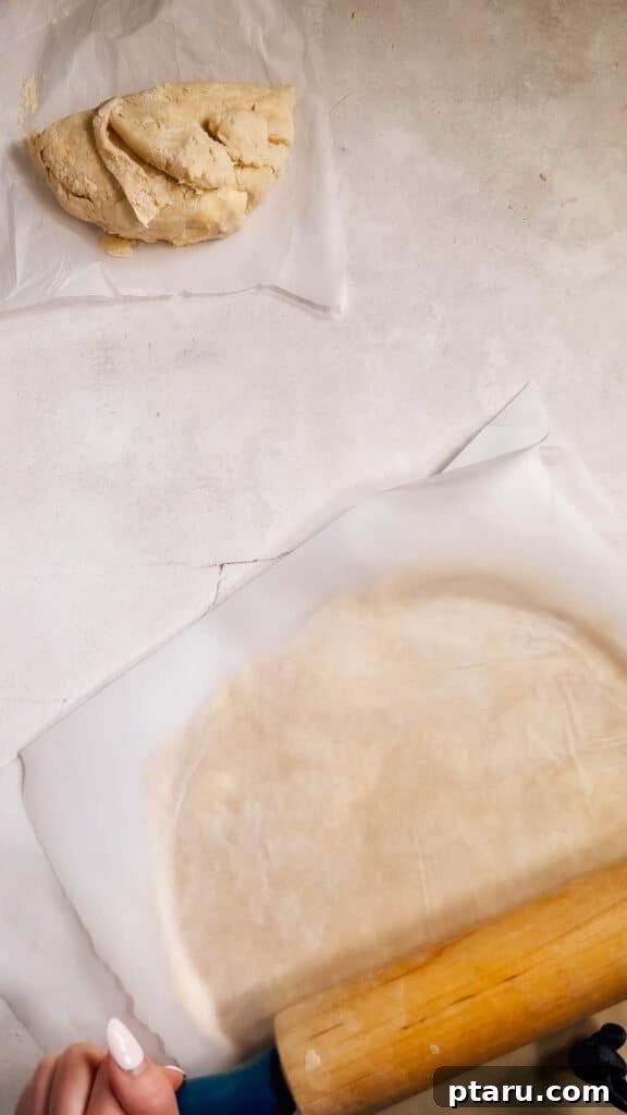 Simple Hand-Mixed Pie Crust 15 Rolled out pie dough between two sheets of parchment paper, showing even thickness and smooth edges.