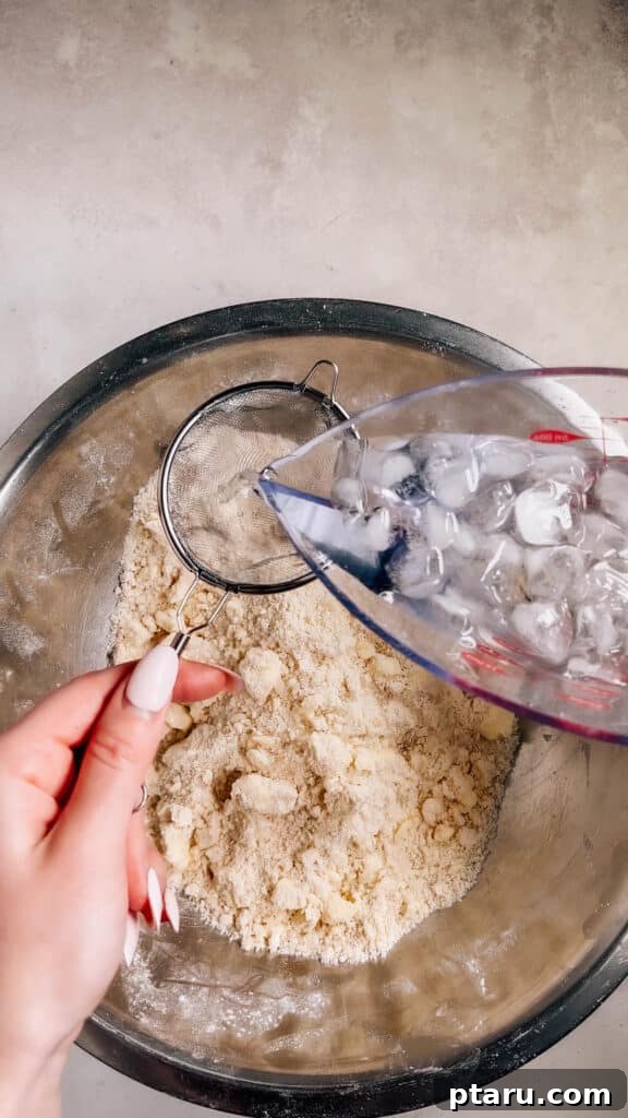 Simple Hand-Mixed Pie Crust 9 Pouring ice water through a sieve into a measuring cup for precise cold water addition.