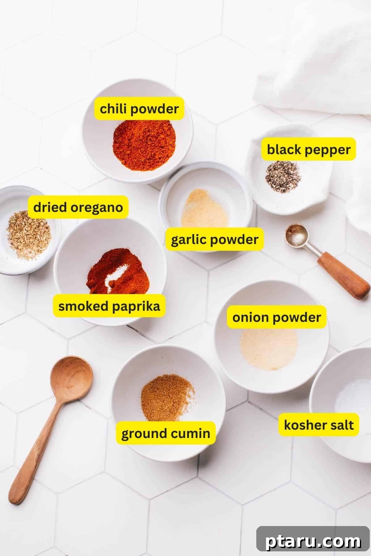 Fiesta Chicken Taco Blend 3 Ingredients for homemade chicken taco seasoning spread out on a kitchen countertop, including chili powder, black pepper, dried oregano, garlic powder, smoked paprika, onion powder, ground cumin, and kosher salt.