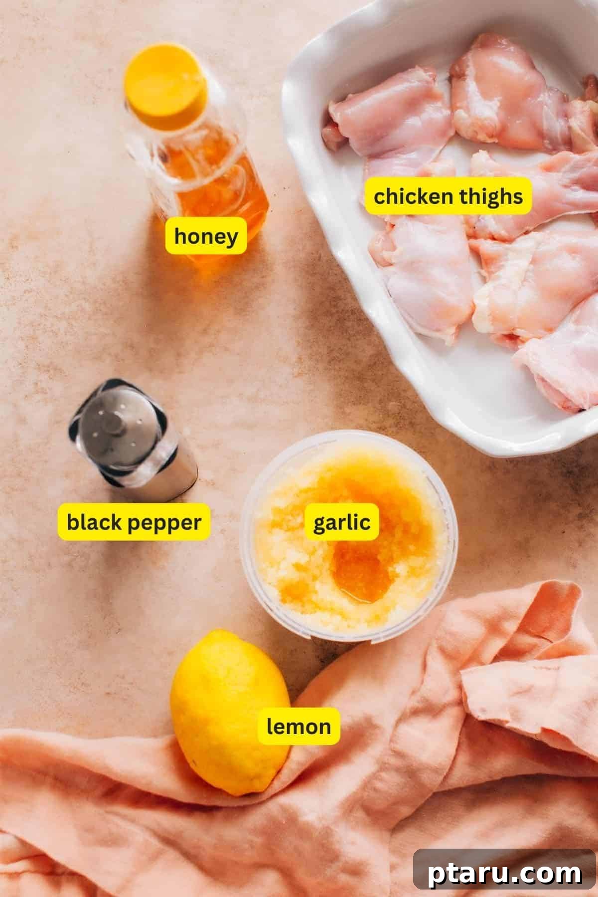 Sticky Honey Garlic Lemon Pepper Chicken Thighs 3 Ingredients for Honey Garlic Lemon Pepper Chicken Thighs laid out on a kitchen countertop, including honey, chicken thighs, black pepper, garlic, and lemon, ready for preparation.