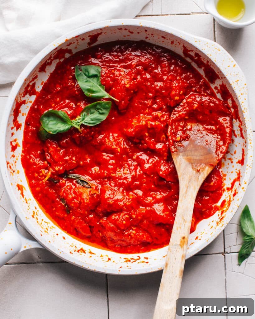 Effortless Air Fryer Pizza For Crispy Perfection 4 Homemade tomato sauce simmering in a white saucepan with a wooden spoon, radiating rich aroma.
