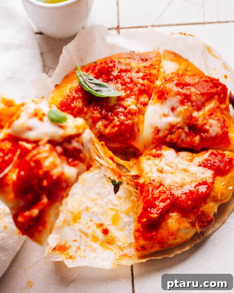 Effortless Air Fryer Pizza For Crispy Perfection 7 A slice of pizza being pulled from the main pie, showing a glorious cheesy stretch.