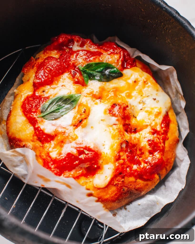 Effortless Air Fryer Pizza For Crispy Perfection 8 Pizza is perfectly cooked with vibrant toppings in an air fryer basket, ready to be removed.