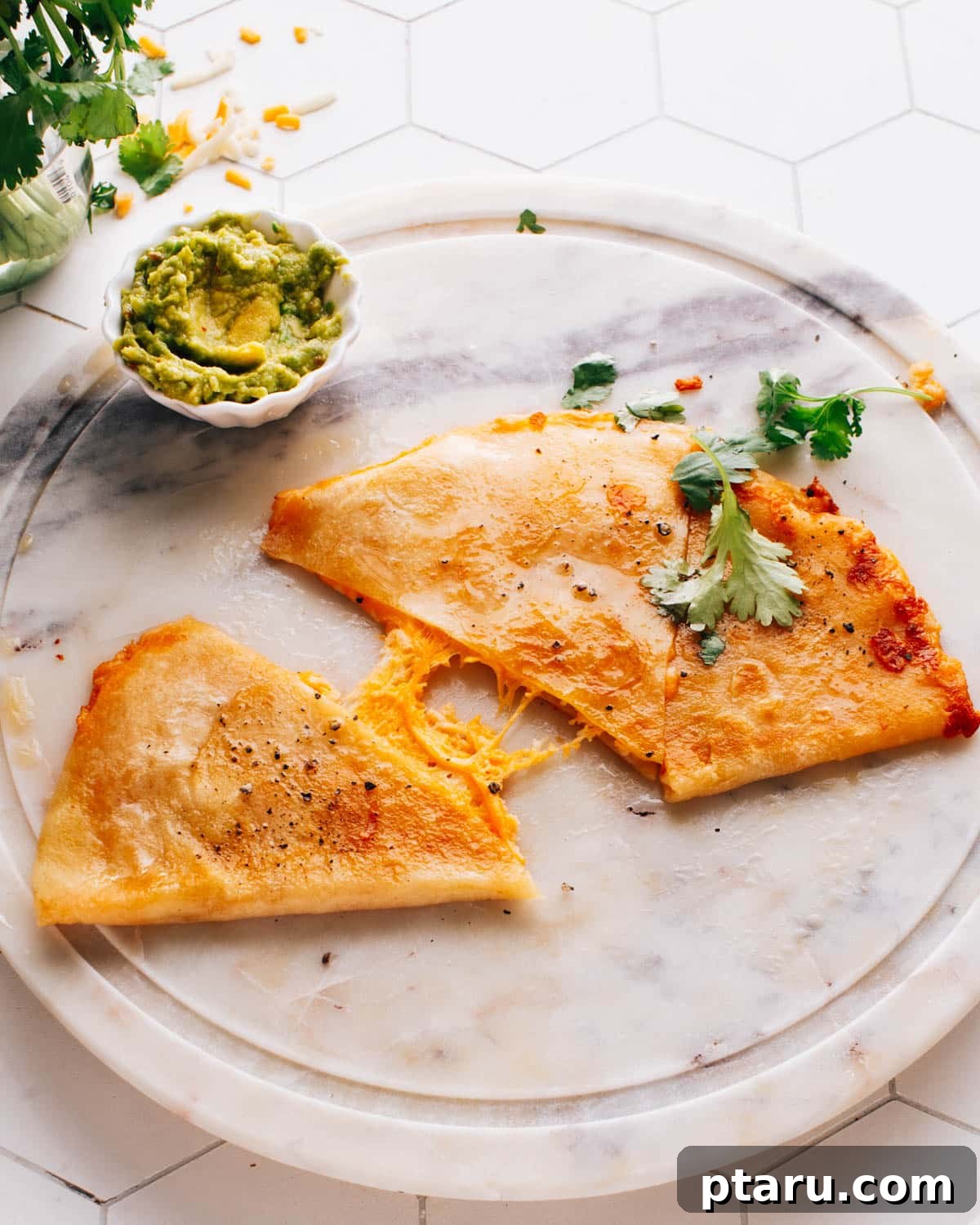 Golden Cheesy Foldover 5 A serving of perfectly cooked cheese quesadilla wedges, accompanied by a small container of creamy avocado crema for dipping.
