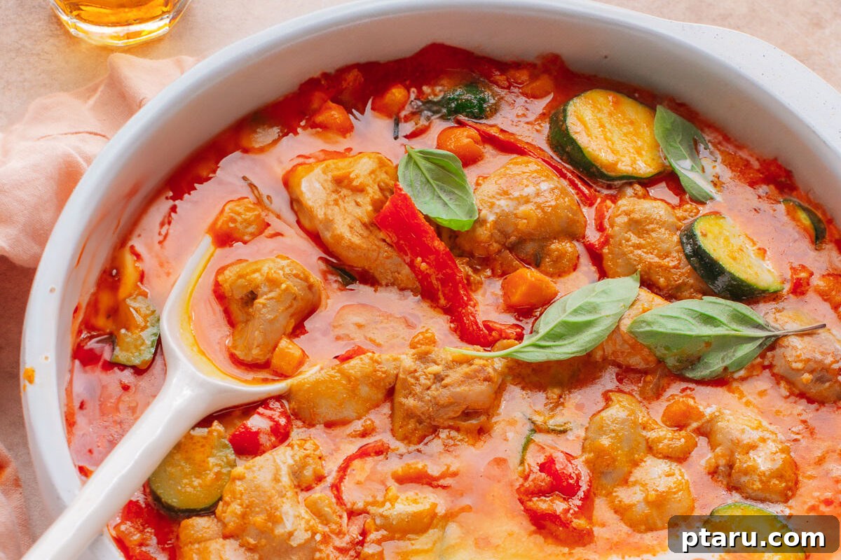 Effortless 20-Minute Red Curry 2 A vibrant red curry chicken dish in a pan, ready to be served, with a spoon dipping in to highlight its rich texture.