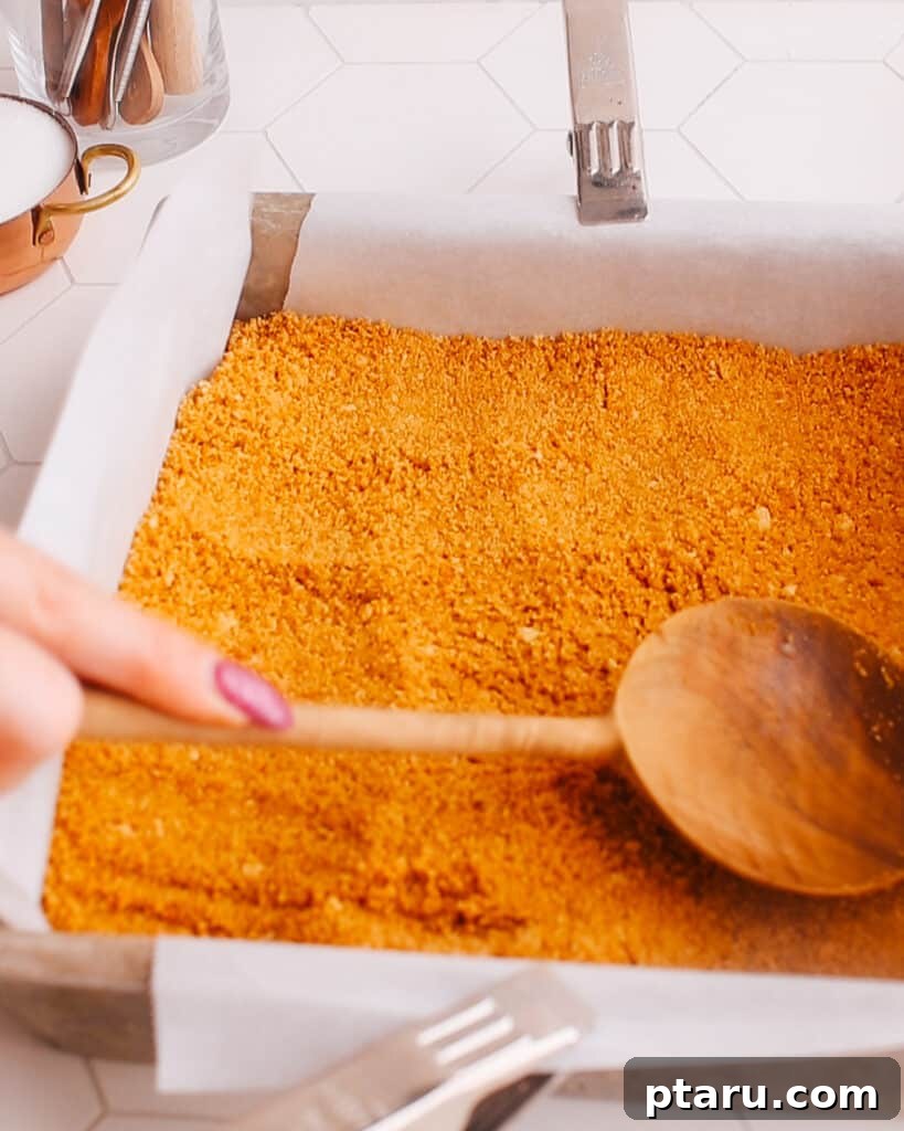 Easy Pumpkin Cheesecake Bars 4 Pressing the graham cracker crust into a baking pan.